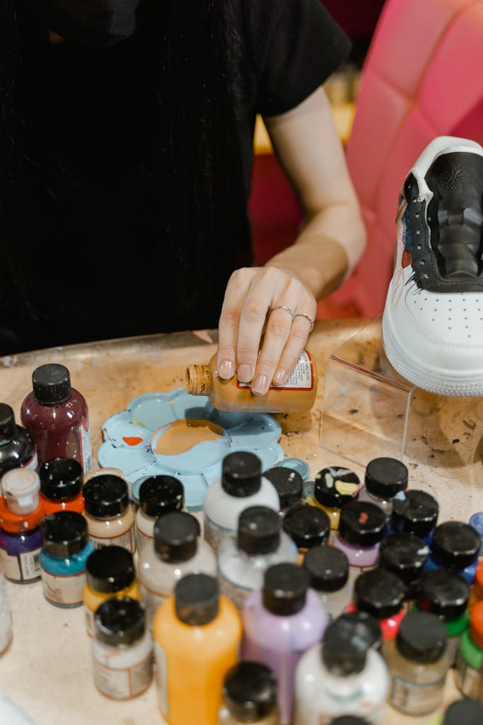 A young artist skillfully blends paints on a palette, preparing to design a unique shoe.