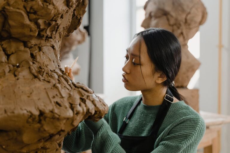 Focused artist working on detailed clay sculpture in an art studio. Creative process captured.
